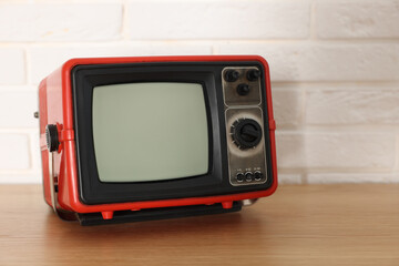 Obraz premium Retro tv set on wooden shelf against white brick wall