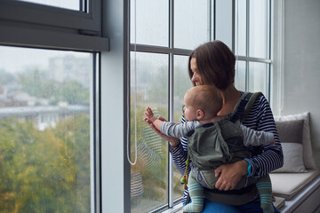 Mother and child observe rain from a cozy window on a calm day