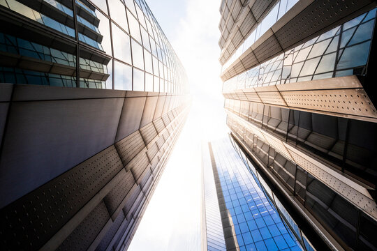 This image offers an upward perspective of two modern skyscrapers stretching towards a radiant sky, illustrating the concept of reaching for new heights in a cityscape.