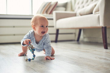 Happy crawling baby explores living room with colorful toy on a bright and sunny day