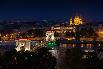 Budapest landscape during blue hour. Beautiful view from above of Danube river and iconic Széchenyi Chain Bridge light in the color of the national flag of Hungary and Parliament. Travel to Budapest. 