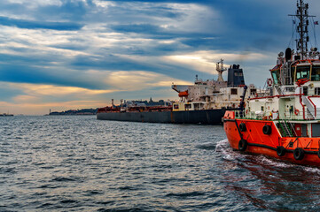 Fototapeta premium A large tanker ship and tug boat sails along the Bosphorus against the background of Istanbul, Turkey, a view from a pleasure boat