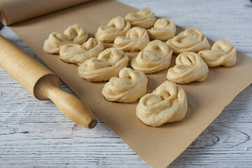 Fresh homemade buns moulded on baking paper using a rolling pin.