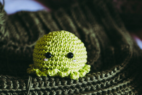 Atelier de crochet avec des travaux en cours, jouet petite pieuvre vert color&eacute; en crochet
