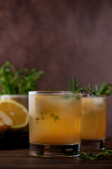 Pear lemonade with lemon, rosemary, thyme and ice on a wooden table. Healthy drink, sugar and alcohol free. Vertical orientation.
