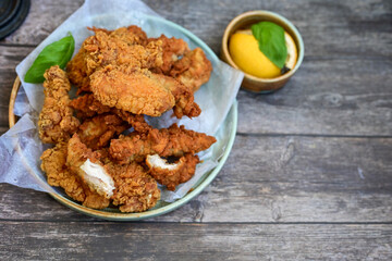 
 Crispy home made  deep fried   chicken strips . Breaded  with cornflakes chicken  breast fillets  with chilly peppers and fresh   basil on wooden rustic background