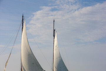 Obraz premium Ocean liner or Sea sailing ship concept, Selective focus of white boat canvas with rops on spar, Sailcloth of sailboat with mainmast and boat hoist rope to spread the sails with blue sky as background