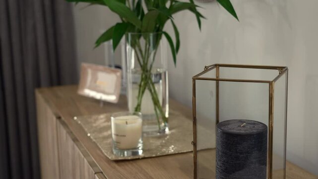 A casual moving and tilting transitional shot from a candle in a home to a flower in a vase