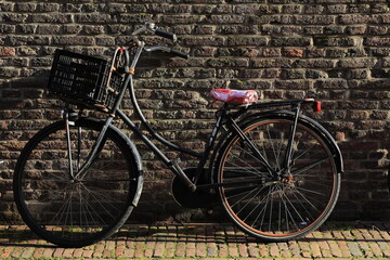 Obraz premium Black Retro Bicycle Parked Against a Brick Wall in Amsterdam, Netherlands