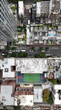 An impressive vertical orientation top-down drone shot of W 52nd Street in New York City, capturing the bustling city streets, skyscrapers, and iconic urban grid of Manhattan.