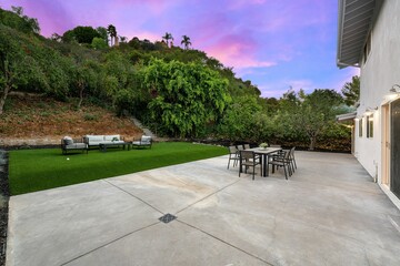 Backyard patio with modern furniture and sunset sky.