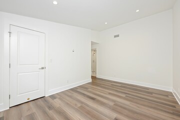 Obraz premium Minimalist empty room with wooden floor and closed door.