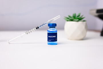 blue vaccine with syringe on top of it on a white table. health and medical concept