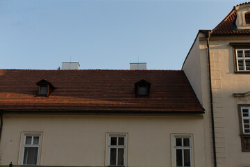 Obraz premium A striking roofline with varied windows and distinct chimneys stands out against a clear blue sky, showcasing the extraordinary architecture of timeless historical buildings