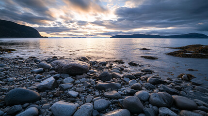 Obraz premium Stunning sunset over rocky shore with calm water and striking sky colors