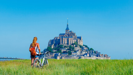 Abbey Mont Saint-Michel, Normandy in France, female tourist in bicycle looking at the view