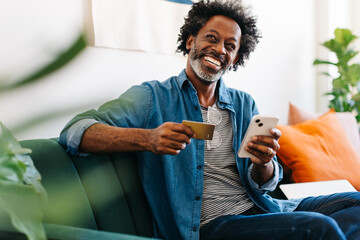 Online shopping: Mature black man using an ecommerce app on his smartphone at home