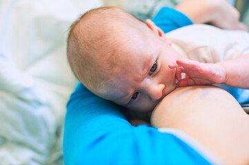 Infant breastfeeding session in a cozy indoor setting with warm lighting and nurturing atmosphere