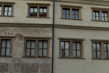 Obraz premium The facade of a historic building displays an array of elegant windows and beautifully detailed frescoes, drawing attention to its remarkable architectural features and urban design aspects