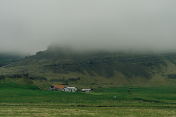 Fototapeta premium rural scene with grazing sheep,rustic farm buildings and a tranquil lake,capturing Iceland countryside charm.