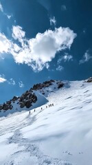 Obraz premium Snow-covered mountain landscape with climbers ascending under a bright blue sky during winter
