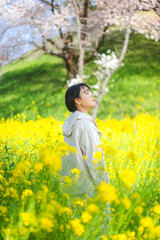 Fototapeta premium Woman standing relax and calm in yellow flower blossom field leisure in nature on spring season