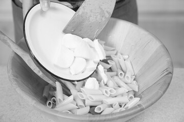 Person adding mozzarella to pasta