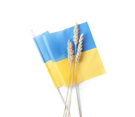 Fototapeta premium Ears of wheat and Ukrainian national flag isolated on white, top view