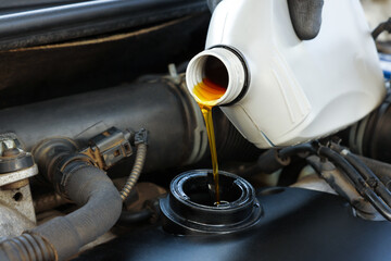 Man pouring motor oil into car engine, closeup