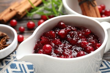 Tasty cranberry sauce in gravy boat on table, closeup