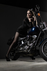 Confident woman posing on motorcycle in dramatic light