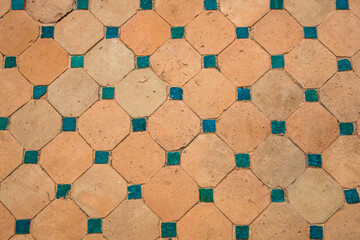 Rustic terracotta tiles adorned with teal ceramic square accents, weathered texture, design element...
