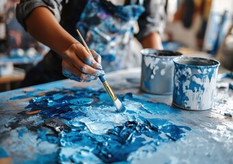Fototapeta premium A person is painting a blue and white canvas with a brush. The painting is in progress and the person is using a blue and white paint
