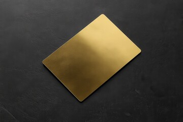 A gold card with a shiny surface sits on a black table. The card is rectangular in shape and he is...