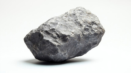 Obraz premium Close-up of a rugged, textured grey rock against a plain white background, showcasing its natural form and rough surface features clearly.