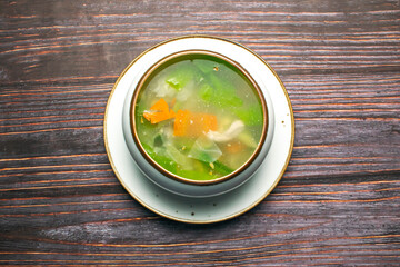 Chicken Vegetable soup include cabbage, carrot and belle pepper served in broth isolated on wooden table top view of bangladeshi and thai food
