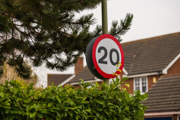 20 miles per hour sign behind a bush