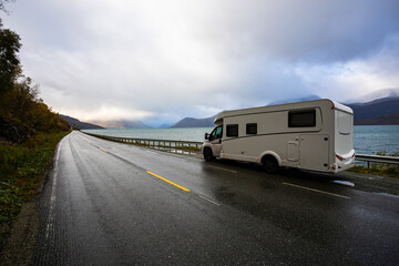 Naklejka premium A motorhome parked by the road in the autumn landscape of the Lyngen Alps, Northern Norway, with mountains.