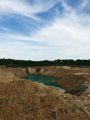 Obraz premium Peaceful landscape with water in a quarry under azure sky