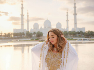 Travel to the United Arab Emirates, Abu Dhabi. Woman in white Arabic dress looking at Sheikh Zayed...