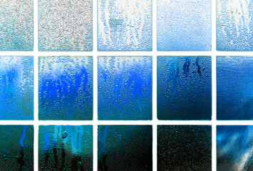 Window with dew and water droplets in negatively inverted colors. Surreal background with glass structures and white frames in shades of blue and cyan. Surreal background in intense colors.