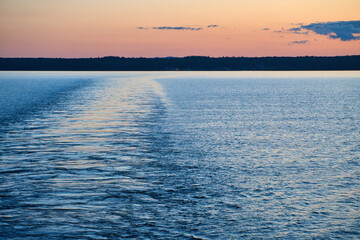 Obraz premium View from a ship departing from an island on the sea at sunset. Scandinavian