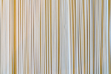 Obraz premium Close-up of vertical udon noodle, wooden sticks in parallel arrangement. Textured abstract pattern. Neutral background for design.