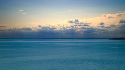 Obraz premium Tranquil seascape under a clear sky. The water reflects gentle clouds