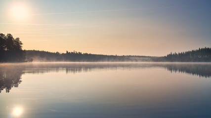 Lake in Sweden, mirror-smooth water with romantic light and trees on the shore