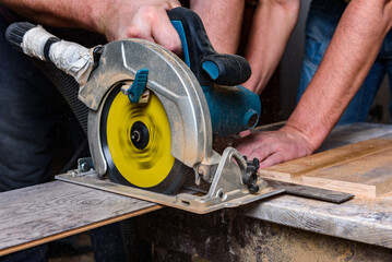 Construction worker using circular saw to cutting laminate for installation.