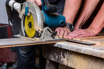 Construction worker using circular saw to cutting laminate for installation.