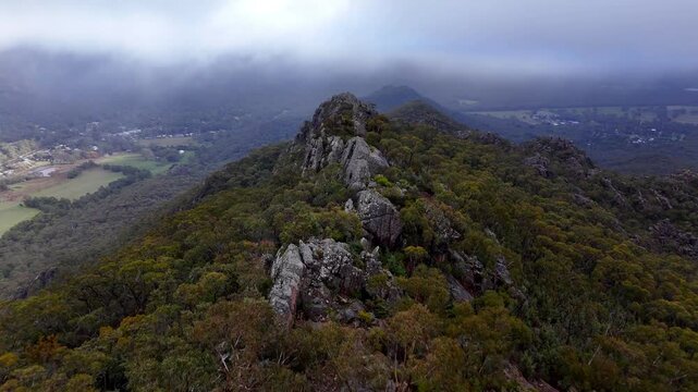 Aerial footage of Grampians National Park at dawn, gliding through the mountain forests, revealing majestic natural rock formations, peaks, and valley landscapes