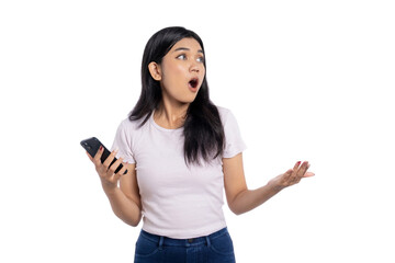 Beautiful young Asian woman holding a smartphone with a surprised expression, looking away at empty space isolated on white background