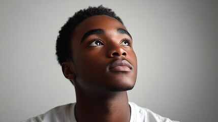 Obraz premium Young man gazing up, hopeful expression, ample light, clear back